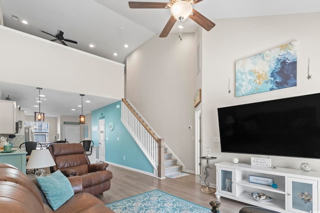 living room with baseboards, stairs, a high ceiling, wood finished floors, and a ceiling fan