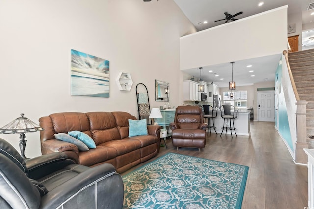 living room featuring visible vents, stairs, a high ceiling, wood finished floors, and a ceiling fan