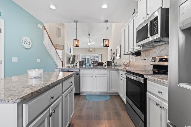 kitchen featuring visible vents, light stone counters, dark wood-style floors, appliances with stainless steel finishes, and ceiling fan