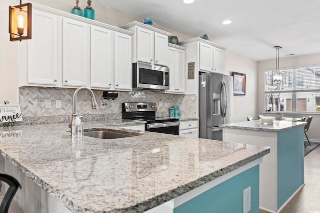 kitchen with tasteful backsplash, a kitchen island, appliances with stainless steel finishes, a peninsula, and a sink