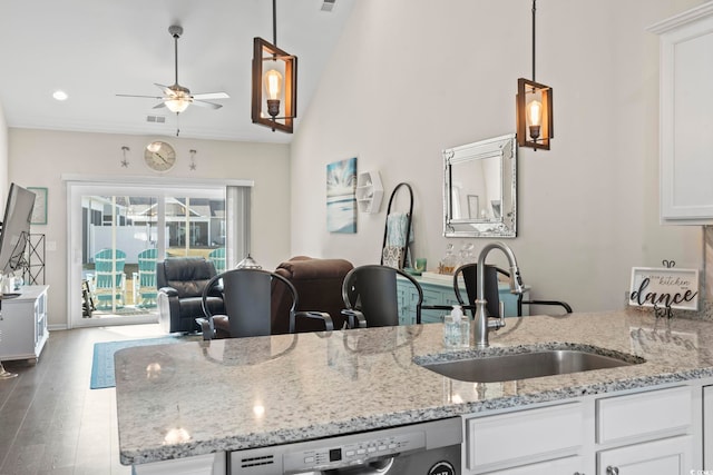 kitchen with a sink, ceiling fan, open floor plan, white cabinets, and stainless steel dishwasher