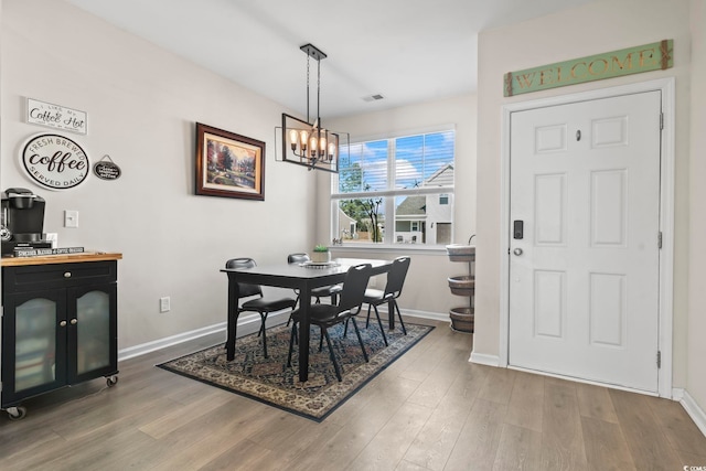 dining room with wood finished floors, baseboards, and a chandelier