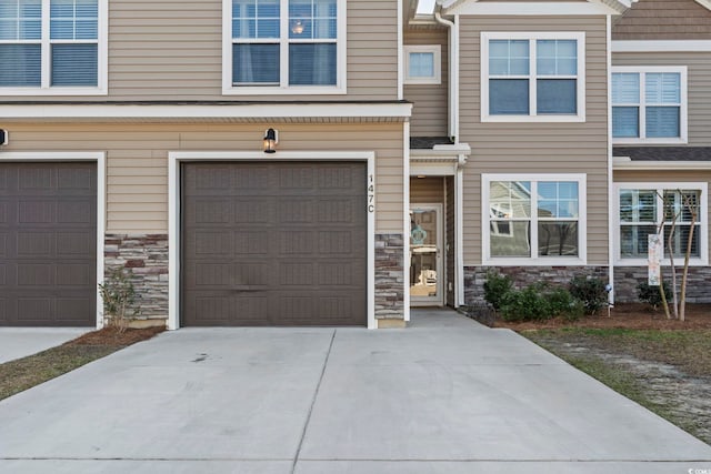 view of front of property featuring a garage, stone siding, and concrete driveway