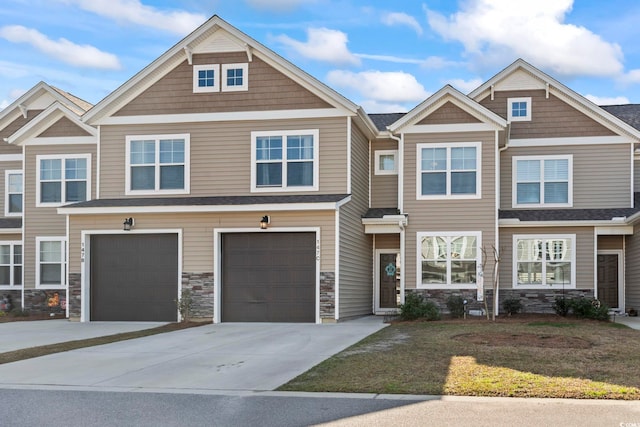 view of property with a garage, stone siding, and driveway