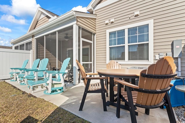 view of patio featuring outdoor dining space, fence, and a sunroom