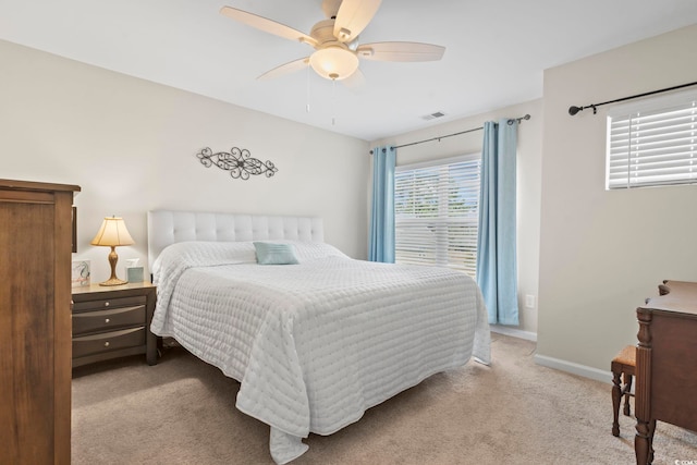 bedroom with visible vents, baseboards, light colored carpet, and a ceiling fan