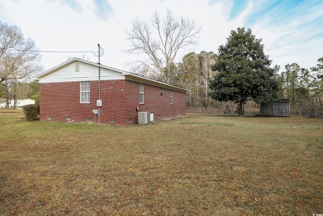 view of side of home featuring brick siding, central air condition unit, and a lawn