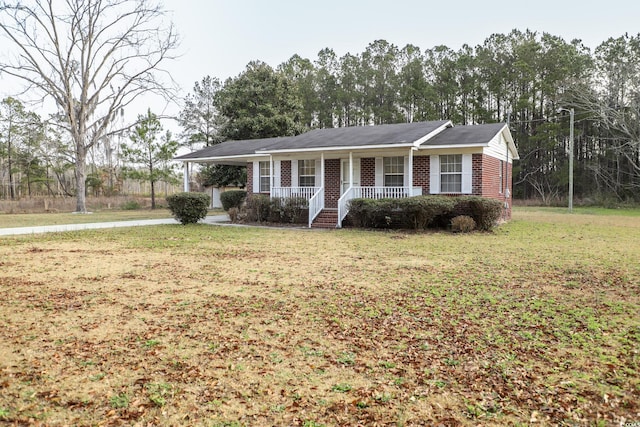 single story home with brick siding, a carport, covered porch, and a front yard