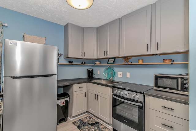 2710 S Ocean Blvd Unit 404, Myrtle Beach, SC 29577 - kitchen with a textured ceiling, dark countertops, appliances with stainless steel finishes, and a sink