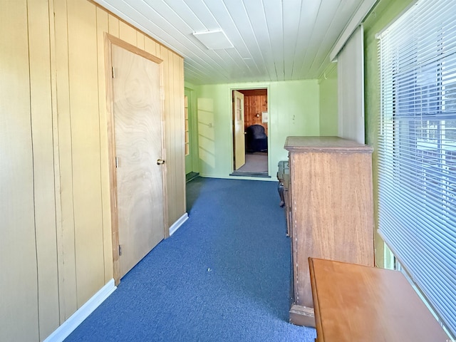 hall with wooden ceiling, carpet flooring, and wood walls