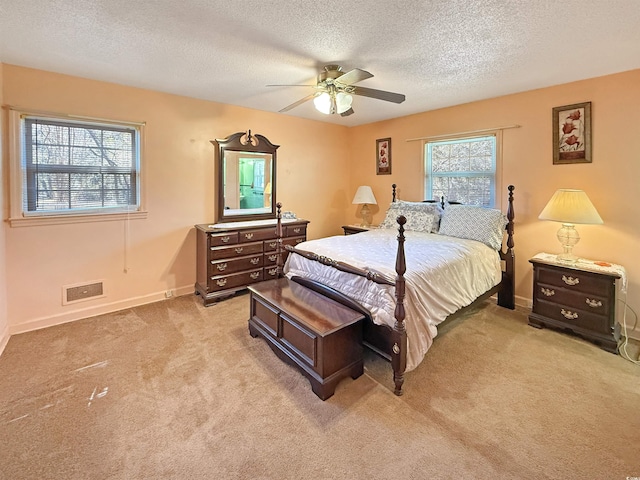 bedroom featuring baseboards, light colored carpet, a ceiling fan, and a textured ceiling