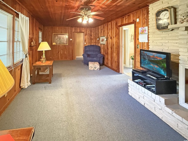 carpeted living room with a fireplace, wooden ceiling, wooden walls, and a ceiling fan