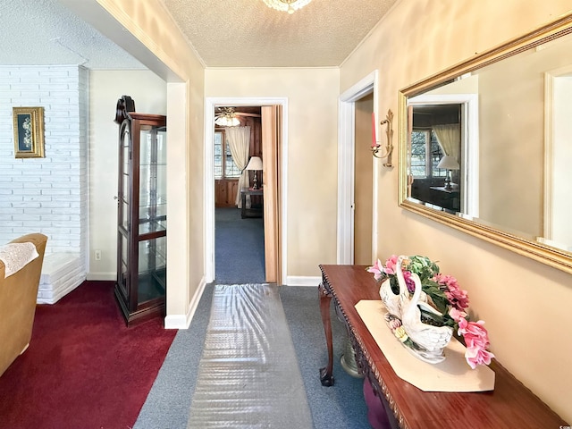 hall featuring dark carpet, a textured ceiling, and baseboards