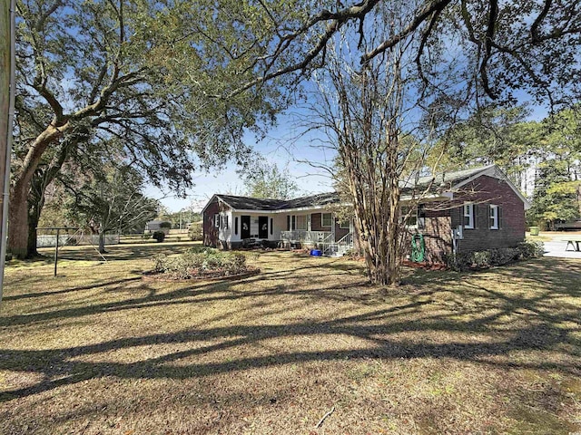 exterior space featuring a front lawn, brick siding, and covered porch