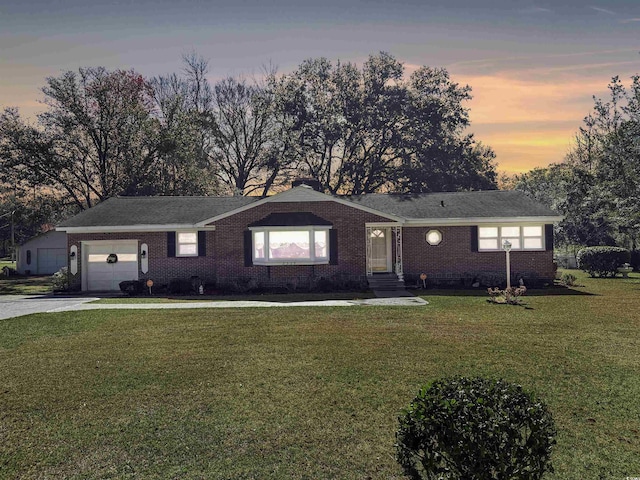 single story home with brick siding, an attached garage, concrete driveway, and a front yard