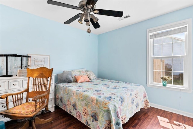 bedroom featuring a ceiling fan, wood finished floors, visible vents, and baseboards