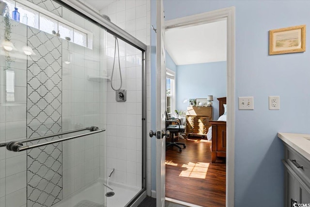 ensuite bathroom with connected bathroom, a stall shower, vanity, and wood finished floors