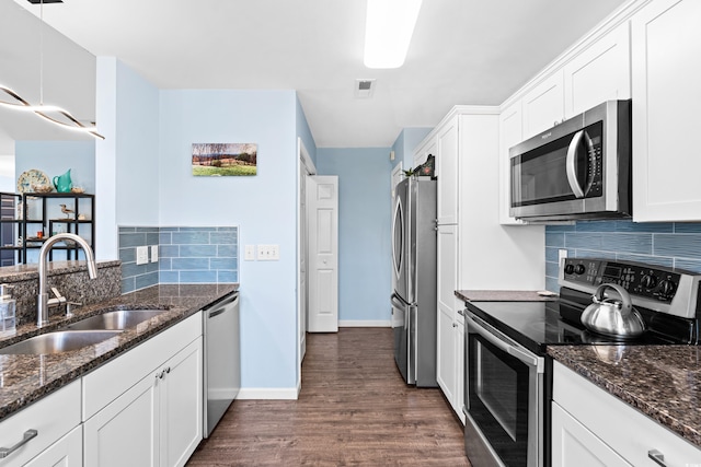 kitchen featuring a sink, stainless steel appliances, backsplash, and dark wood finished floors