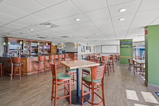 dining room with wood finished floors, visible vents, recessed lighting, a drop ceiling, and a dry bar