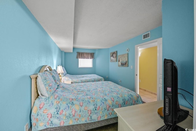 bedroom with tile patterned flooring, visible vents, and a textured ceiling