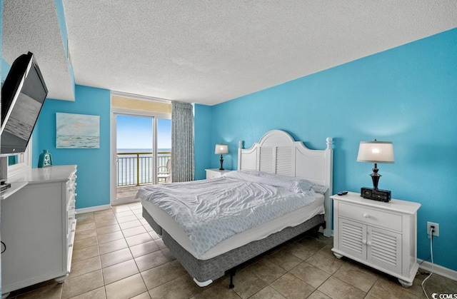 bedroom with access to exterior, tile patterned flooring, a textured ceiling, and baseboards