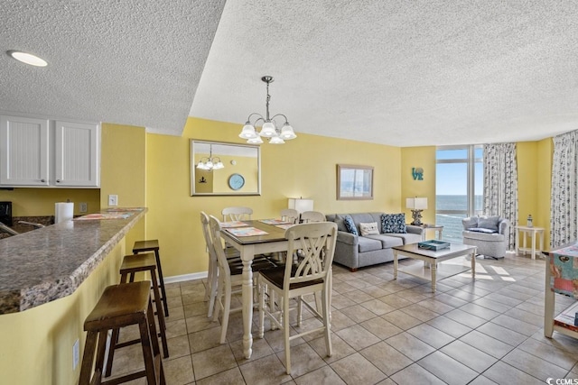 dining room with tile patterned flooring, a notable chandelier, a textured ceiling, and baseboards