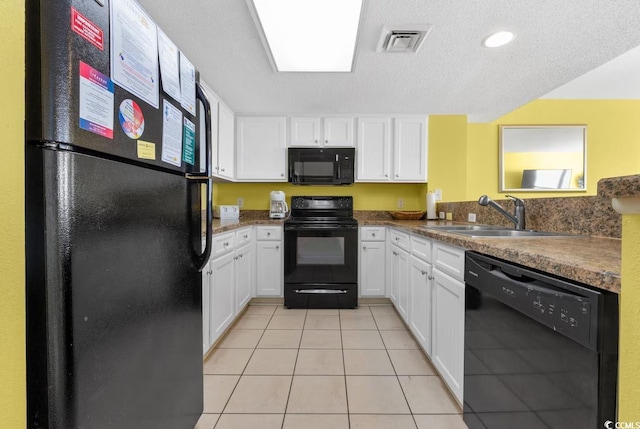 kitchen featuring visible vents, light tile patterned floors, white cabinets, black appliances, and a sink