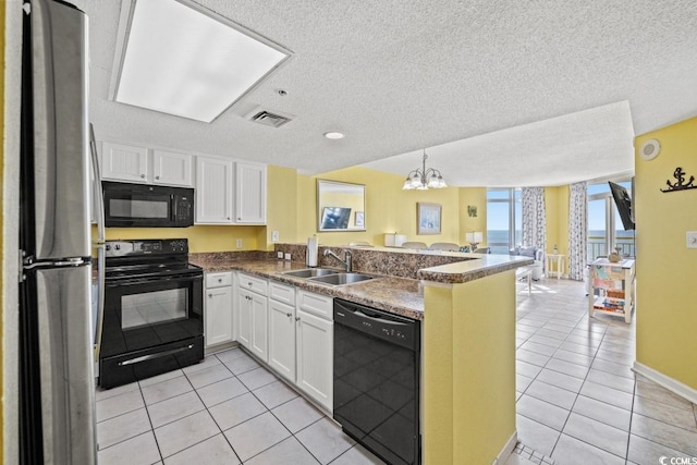 kitchen with visible vents, a peninsula, light tile patterned flooring, black appliances, and a sink