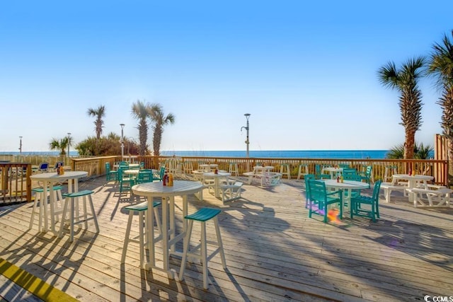 wooden terrace with a water view and outdoor dining space