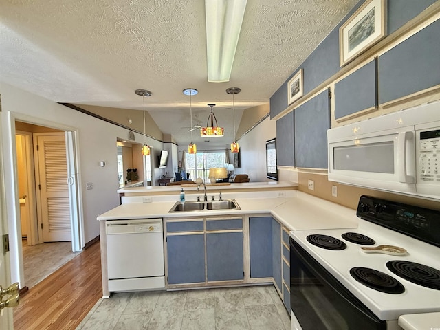 kitchen featuring white appliances, a peninsula, blue cabinetry, lofted ceiling, and a sink