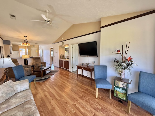 living area featuring vaulted ceiling, visible vents, light wood finished floors, and ceiling fan