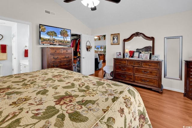 bedroom with visible vents, a walk in closet, wood finished floors, a closet, and lofted ceiling