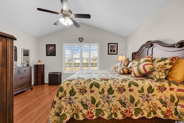 bedroom with a ceiling fan, lofted ceiling, wood finished floors, and a textured ceiling