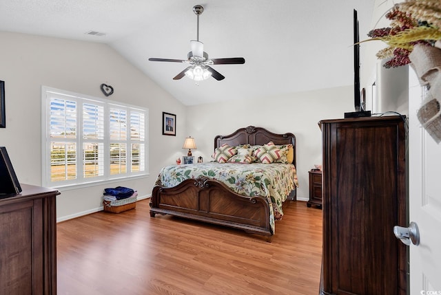 bedroom with baseboards, visible vents, lofted ceiling, light wood-style flooring, and ceiling fan