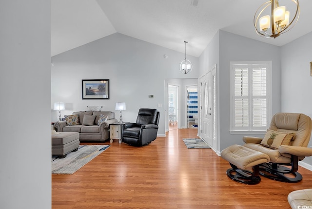 living area with baseboards, light wood-style floors, an inviting chandelier, and high vaulted ceiling