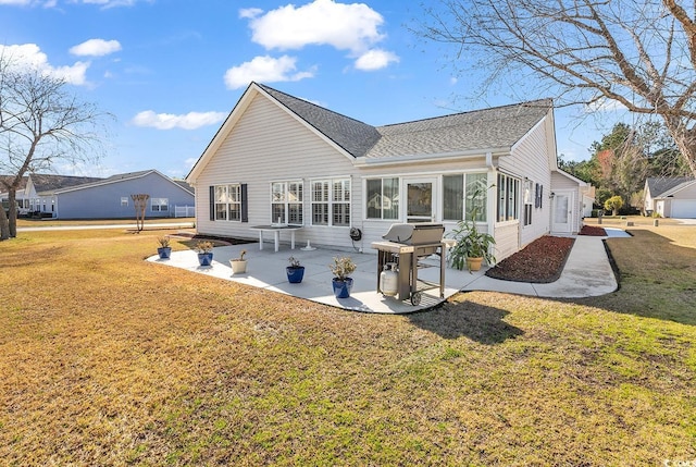 back of property with a lawn, a shingled roof, and a patio