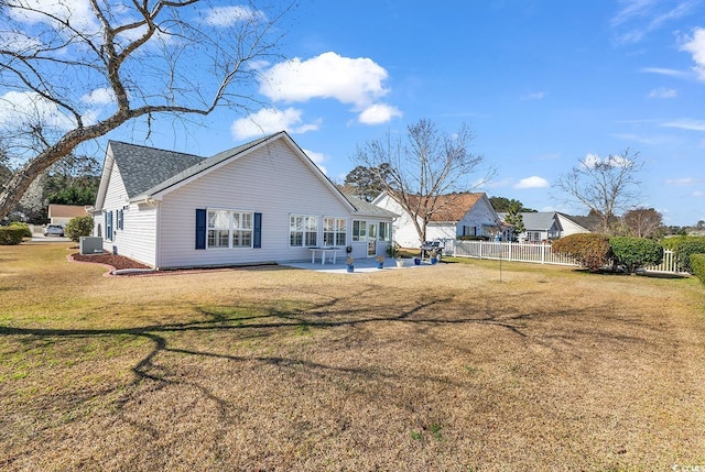 back of property with a patio area, a shingled roof, a yard, and fence