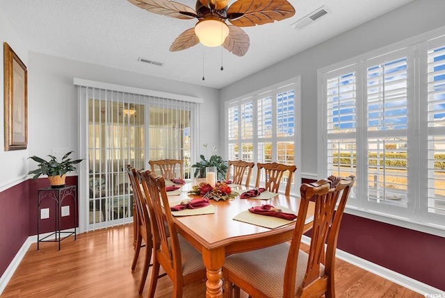 dining space with visible vents, a textured ceiling, wood finished floors, and a ceiling fan