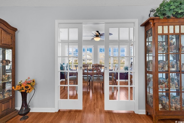 doorway featuring wood finished floors, a ceiling fan, baseboards, french doors, and a textured ceiling