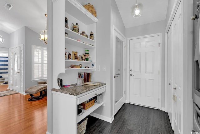 interior space with visible vents, baseboards, dark wood-type flooring, and lofted ceiling