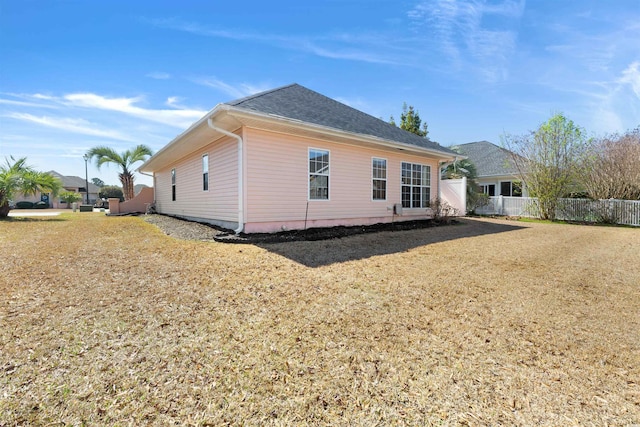 view of side of property featuring roof with shingles and fence