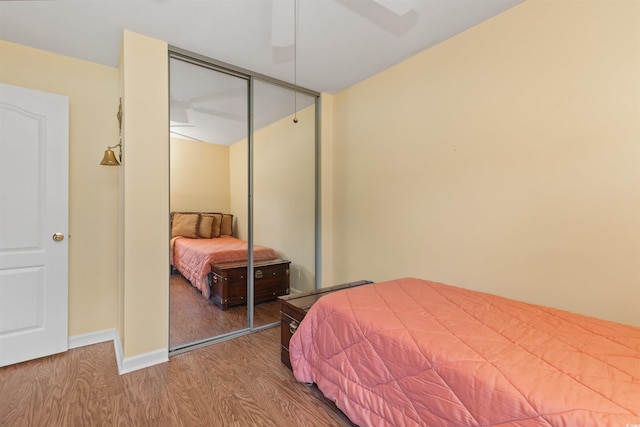 bedroom featuring ceiling fan, a closet, baseboards, and wood finished floors