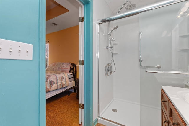 full bathroom featuring vanity, wood finished floors, visible vents, a shower stall, and ensuite bathroom