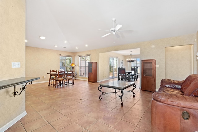 living room with recessed lighting, light tile patterned floors, ceiling fan with notable chandelier, and baseboards