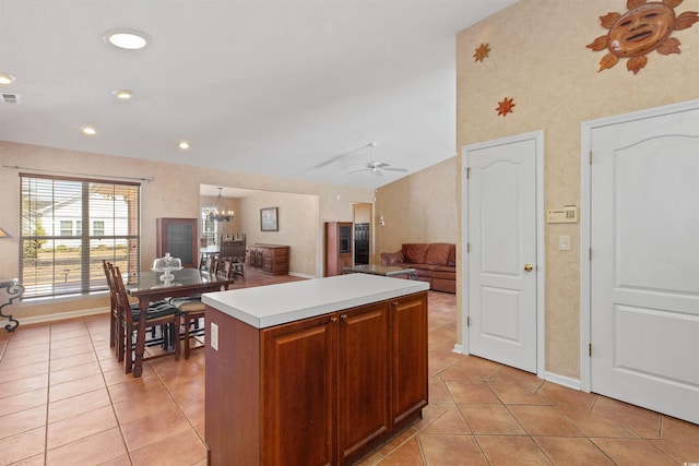 kitchen featuring light tile patterned floors, ceiling fan with notable chandelier, a kitchen island, and light countertops