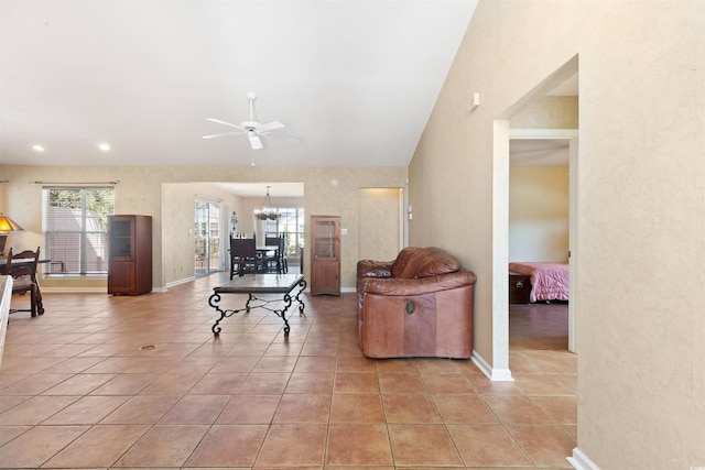 living area with light tile patterned floors, baseboards, lofted ceiling, and ceiling fan with notable chandelier