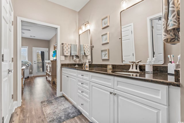 full bathroom featuring a sink, baseboards, wood finished floors, and double vanity