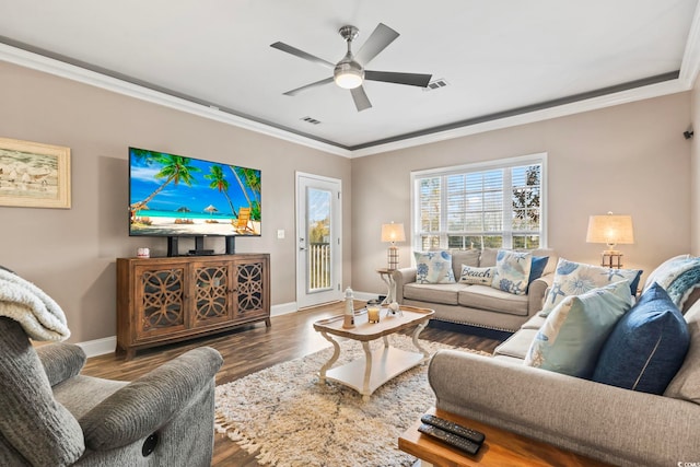 living room featuring ceiling fan, visible vents, wood finished floors, and ornamental molding