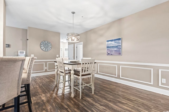 dining room with a decorative wall, a notable chandelier, dark wood-style floors, and wainscoting