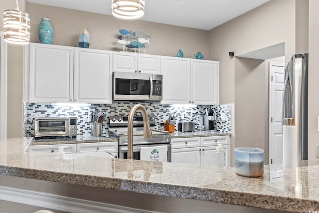 kitchen with a toaster, decorative backsplash, white cabinetry, and stainless steel appliances